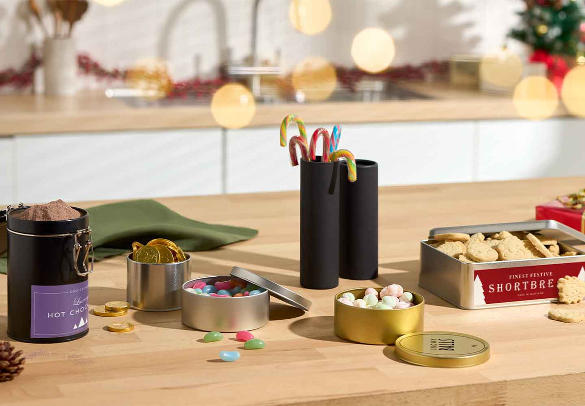 Decorative sweet packaging on a table with a Christmas tree in the background