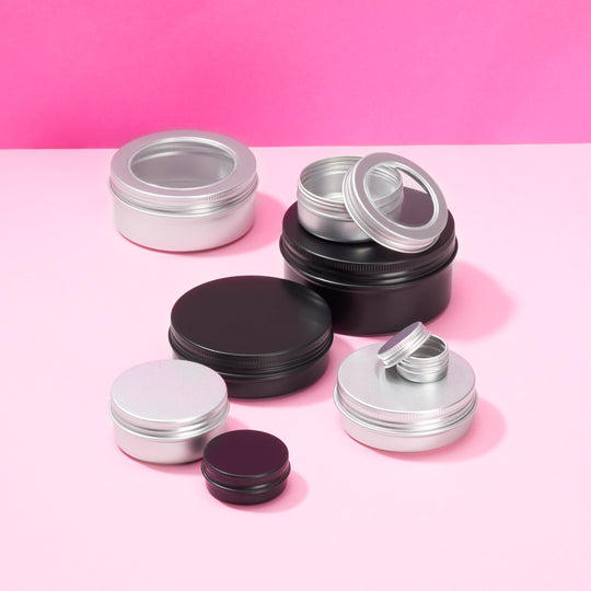 A collection of different sized aluminium screw lid tin packaging in black and silver, some with clear lids.