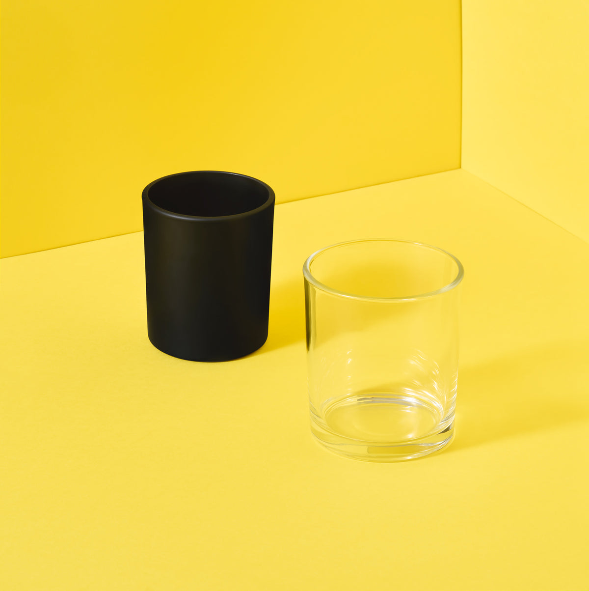 Black and clear candle glass jars on yellow background