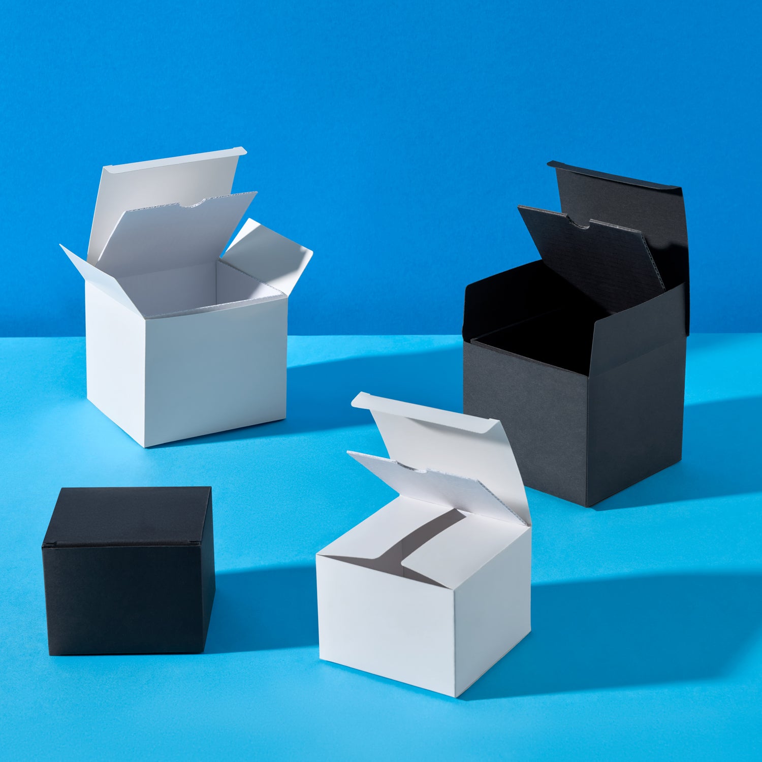 Luxury candle tin boxes in black and white on a blue background. 